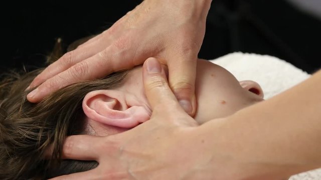 woman receiving head massage at spa center. female doctor doing face massage. 4K
