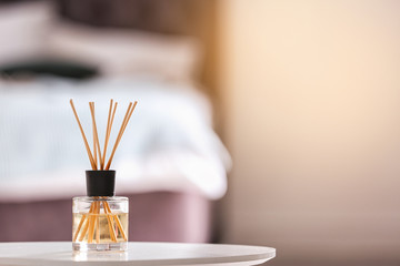 Aromatic reed air freshener on table against blurred background