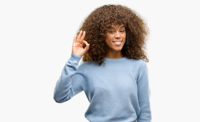 African american woman wearing a sweater smiling positive doing ok sign with hand and fingers. Successful expression.