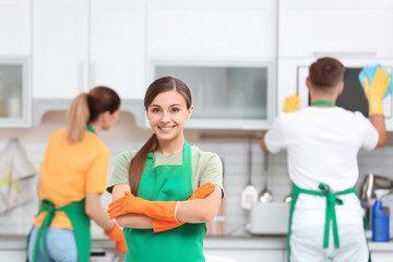 Team of professional janitors in uniform cleaning kitchen