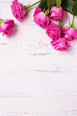 Border from  pink  roses  flowers on white wooden background.