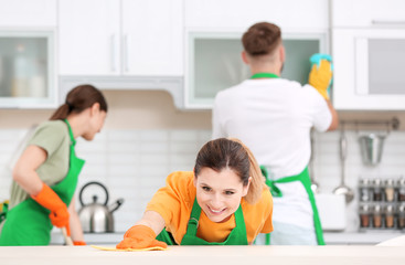 Obraz premium Team of professional janitors in uniform cleaning kitchen