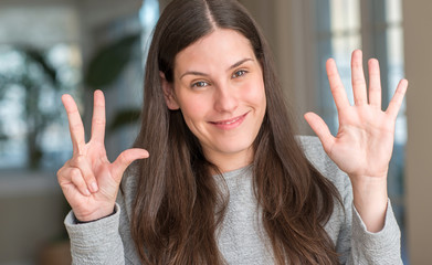 Young beautiful woman at home showing and pointing up with fingers number eight while smiling confident and happy.