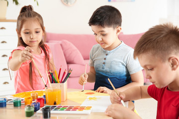 Cute little children painting at table in playing room