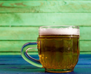 A small mug of beer on a blue wooden background.