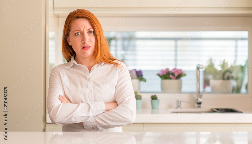 Sticker Redhead woman at kitchen skeptic and nervous, disapproving expression on face with crossed arms. Negative person.