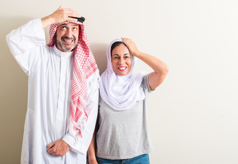 Middle age arabic couple, woman and man stressed with hand on head, shocked with shame and surprise face, angry and frustrated. Fear and upset for mistake.