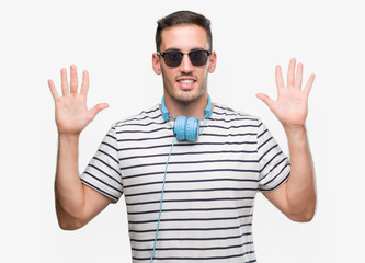 Handsome young man wearing headphones showing and pointing up with fingers number ten while smiling confident and happy.