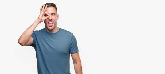 Fototapeta premium Handsome young casual man doing ok gesture with hand smiling, eye looking through fingers with happy face.