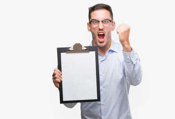 Handsome young business man showing a clipboard annoyed and frustrated shouting with anger, crazy and yelling with raised hand, anger concept