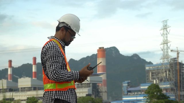 Engineer with a coal power plant in the background, Thailand.