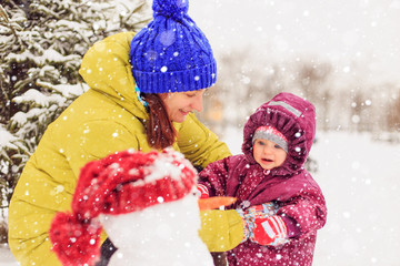 Mom and the baby are playing in the winter park.