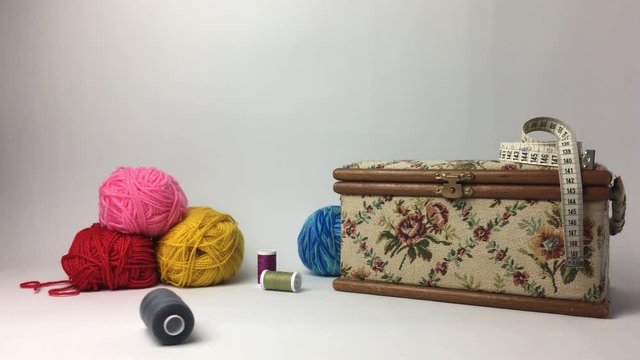 Caja de costura con ovillo de hilo rodando.