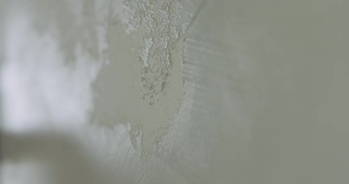Slow motion closeup worker applying decorative concrete plaster on the wall