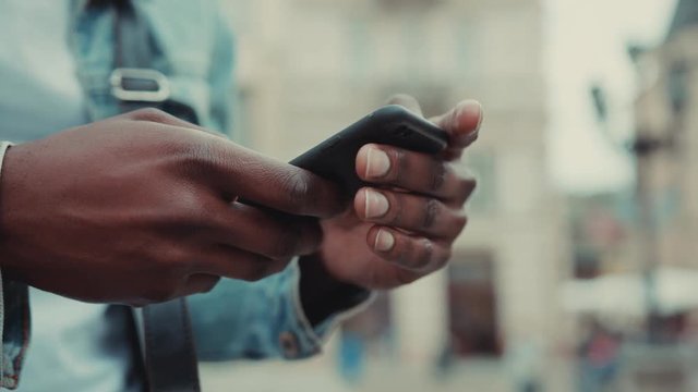 Close up hands young African American man uses the phone at the street business shopping internet face technology call texting mobile smart attractive cell communication slow motion