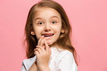 The happy teen girl standing and smiling against pink background.