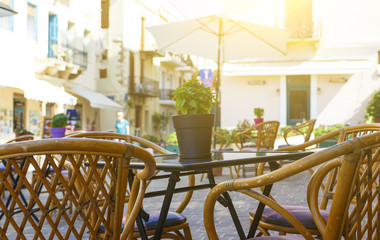 Pot with a flower in center of table on background of Sunny city of Chania. tourists, Crete Greece. depth of field, blur Chania.Street Cafe.