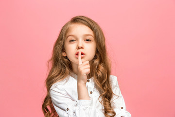 The young teen girl whispering a secret behind her hand over pink background