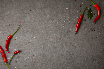 top view of chili peppers and scattered spices on grey table