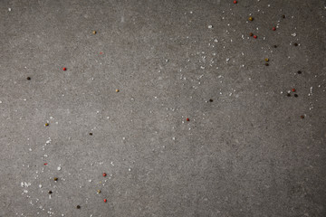 top view of scattered salt and pepper spices on grey table