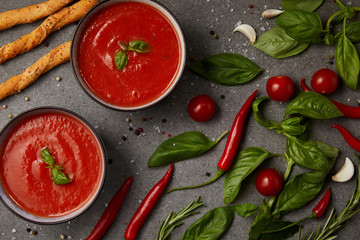 top view of vegetables, bread sticks and appetizing tomato soup on grey surface
