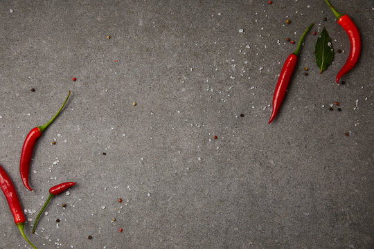 Top View Of Chili Peppers And Scattered Spices On Grey Table