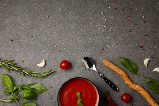 Top View Of Plate With Tasty Tomato Soup And Fresh Tomatoes On Grey Tabletop