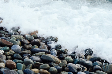 White wave washing the stones of the shore. Background with beach of stone. - 210447752