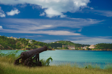 Old cannon in the fort is looking at sea with amazing clouds and island on background