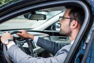 Fototapeta na wymiar side view of businessman in eyeglasses driving car
