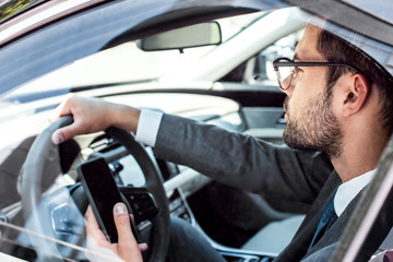 side view of businessman with smartphone driving car