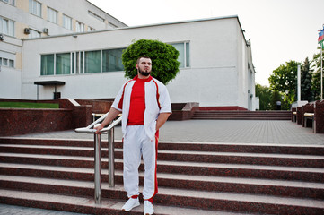 Young brutal bearded muscular man wear on white sport suit with red shirt.