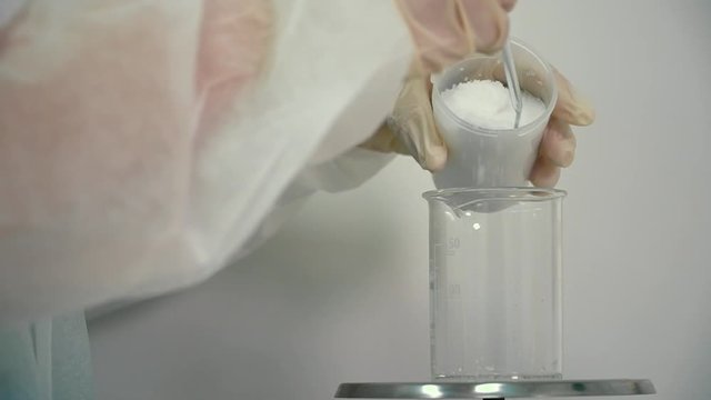 Chemist measuring the weight of the powder at electronic scales in laboratory