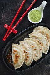 Fried korean dumplings or potstickers, flat-lay on a dark brown stone background, close-up
