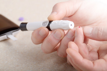 Man Pierce his fingertip before doing blood test with personal glucometer
