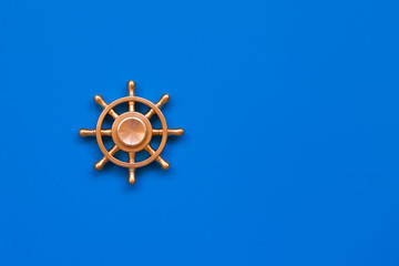Copper yacht steering wheel on blue background. Symbol of leadership. Place for text.