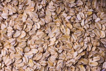 Background of oatmeal. Scattered rolled oats. Close up.