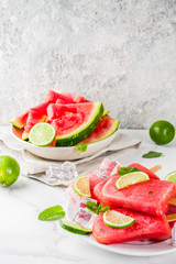 Sweet summer watermelon and lime popsicles with sliced watermelon and mint, on white marble background copy space