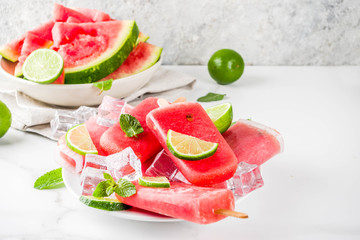 Sweet summer watermelon and lime popsicles with sliced watermelon and mint, on white marble background copy space