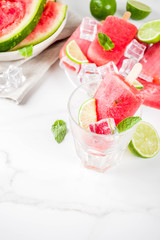 Sweet summer watermelon and lime popsicles with sliced watermelon and mint, on white marble background copy space