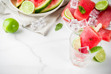 Sweet summer watermelon and lime popsicles with sliced watermelon and mint, on white marble background copy space