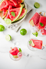 Sweet summer watermelon and lime popsicles with sliced watermelon and mint, on white marble background copy space