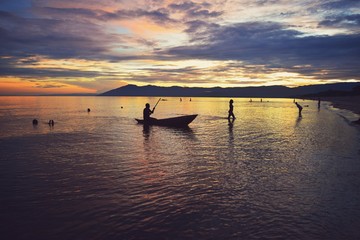 Naklejka na ściany i meble Golden sunset with fishermen at the background at Kande Beach, Lake Malawi, Malawi