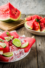 Sweet summer watermelon and lime popsicles with sliced watermelon and mint, on white marble background copy space