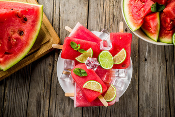 Sweet summer watermelon and lime popsicles with sliced watermelon and mint, on white marble background copy space