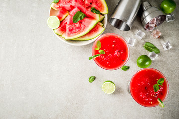 Watermelon margarita cocktail with lime and sliced watermelon, light concrete background copy space