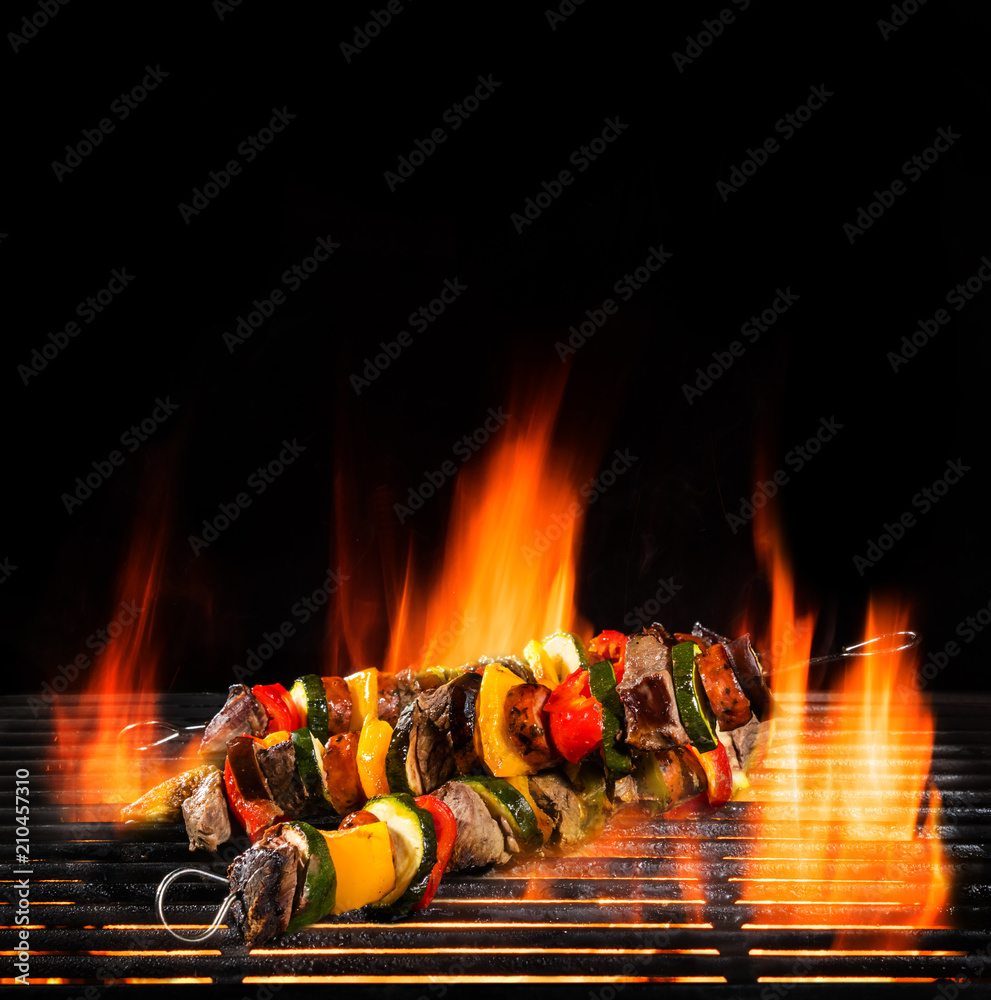 Wall mural delicious skewers on grill with fire flames.