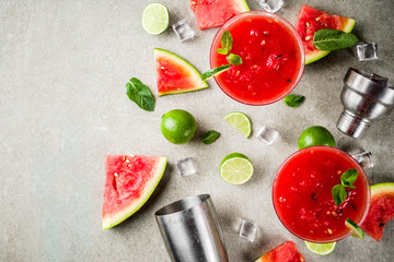 Watermelon margarita cocktail with lime and sliced watermelon, light concrete background copy space