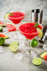 Watermelon margarita cocktail with lime and sliced watermelon, light concrete background copy space