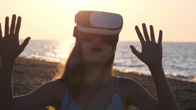 Young Woman Uses A Virtual Reality Glasses On The Beach. Sexy Girl Getting Experience In Using VR-headset At Summer On Sea Background